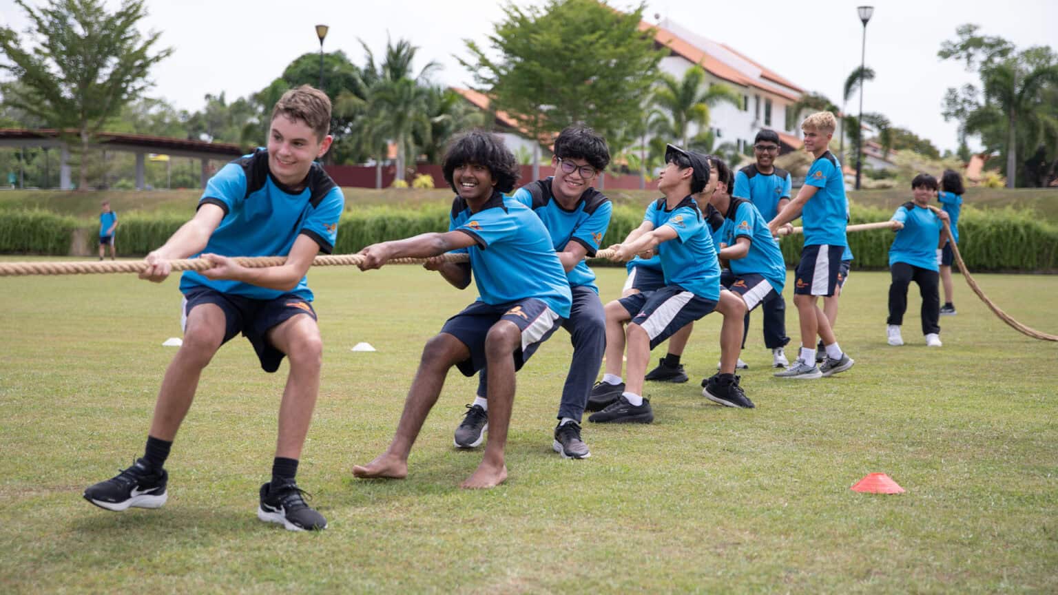 Energetic students participating in tug-of-war at a world schools sports day, fostering teamwork and fitness.