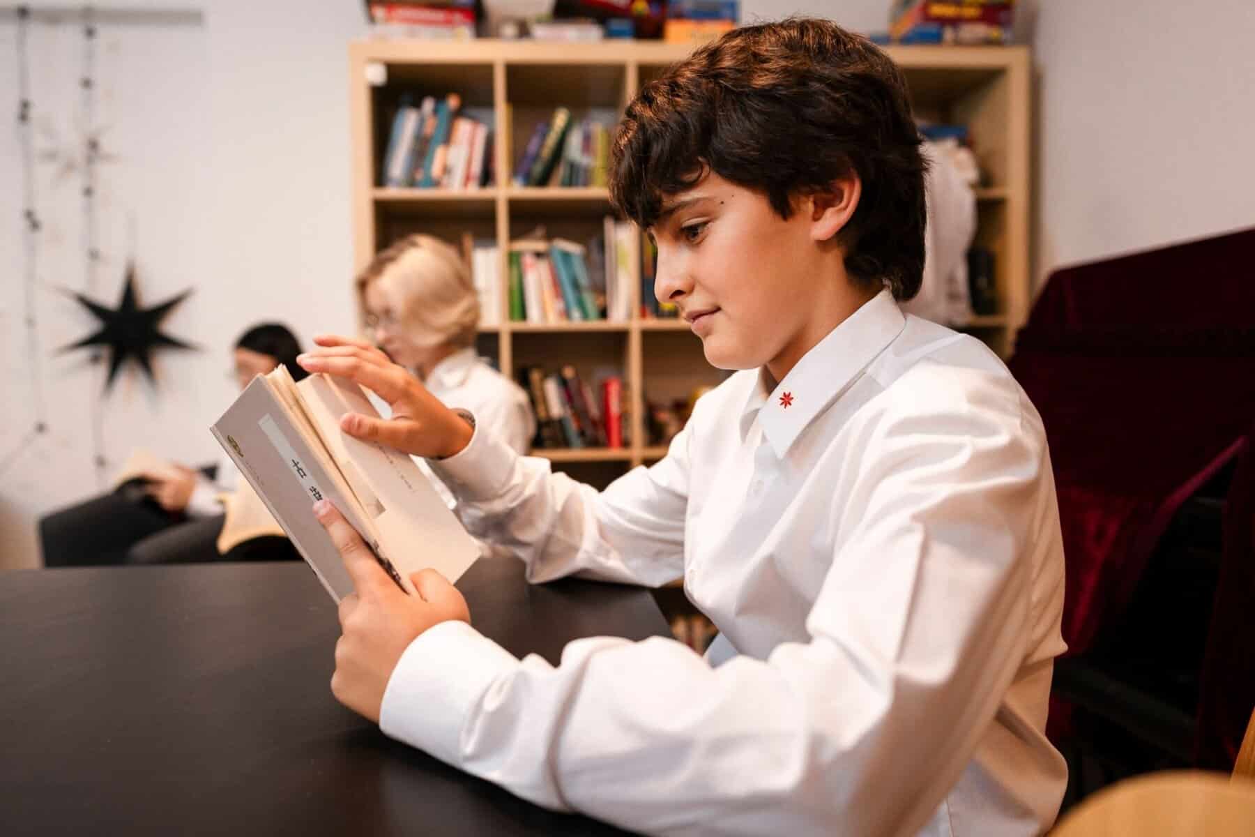 Student reading a book in a library at a world school.