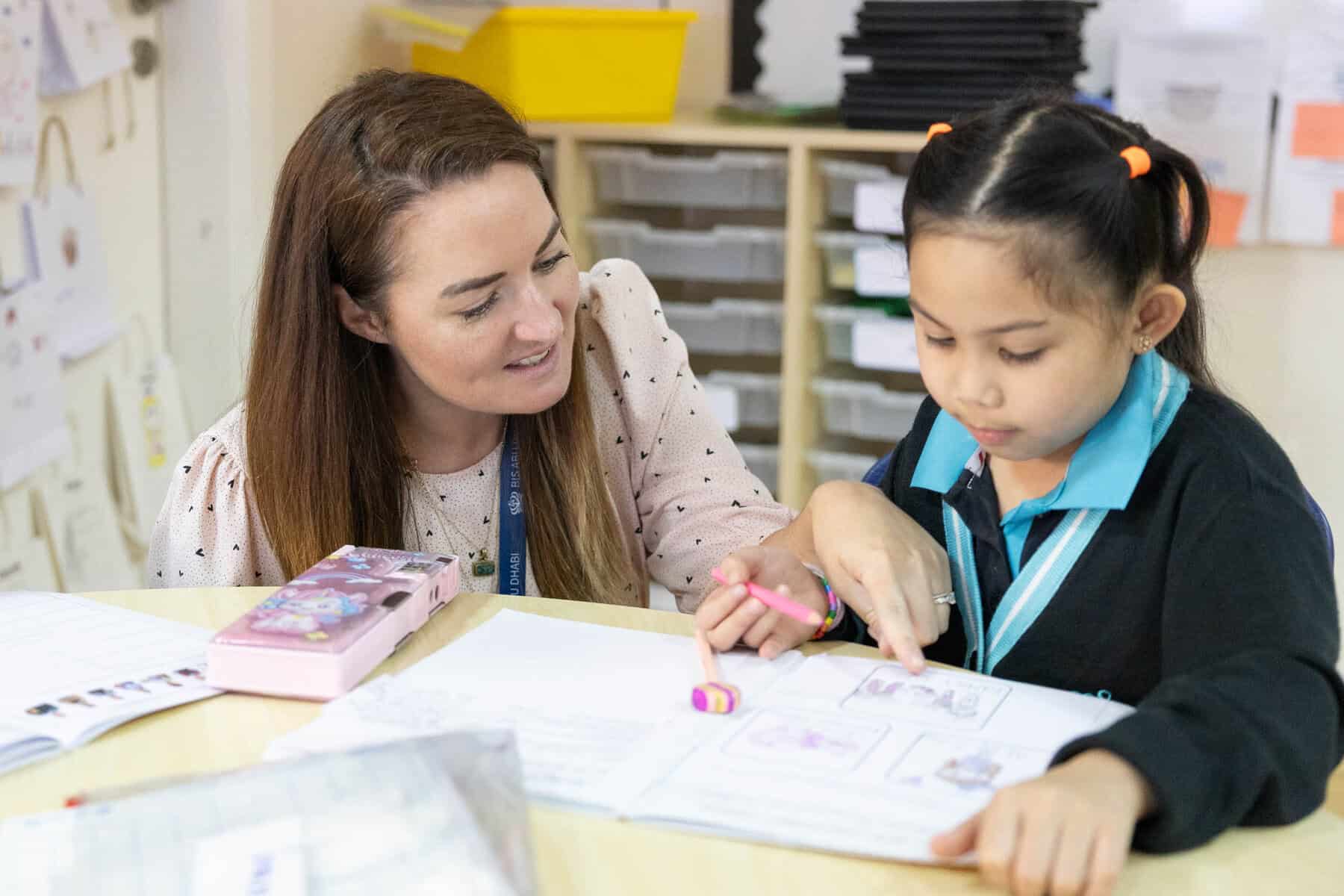 Young girl and teacher engaging in educational activities in classroom.
