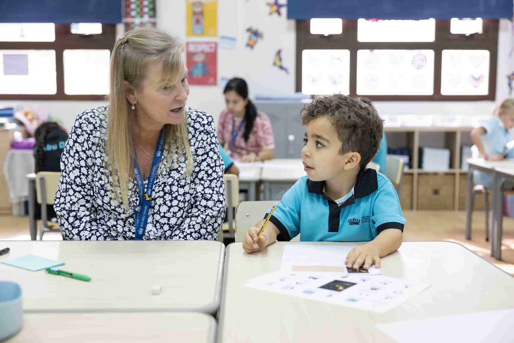 Teacher and young student interacting in a vibrant classroom setting.