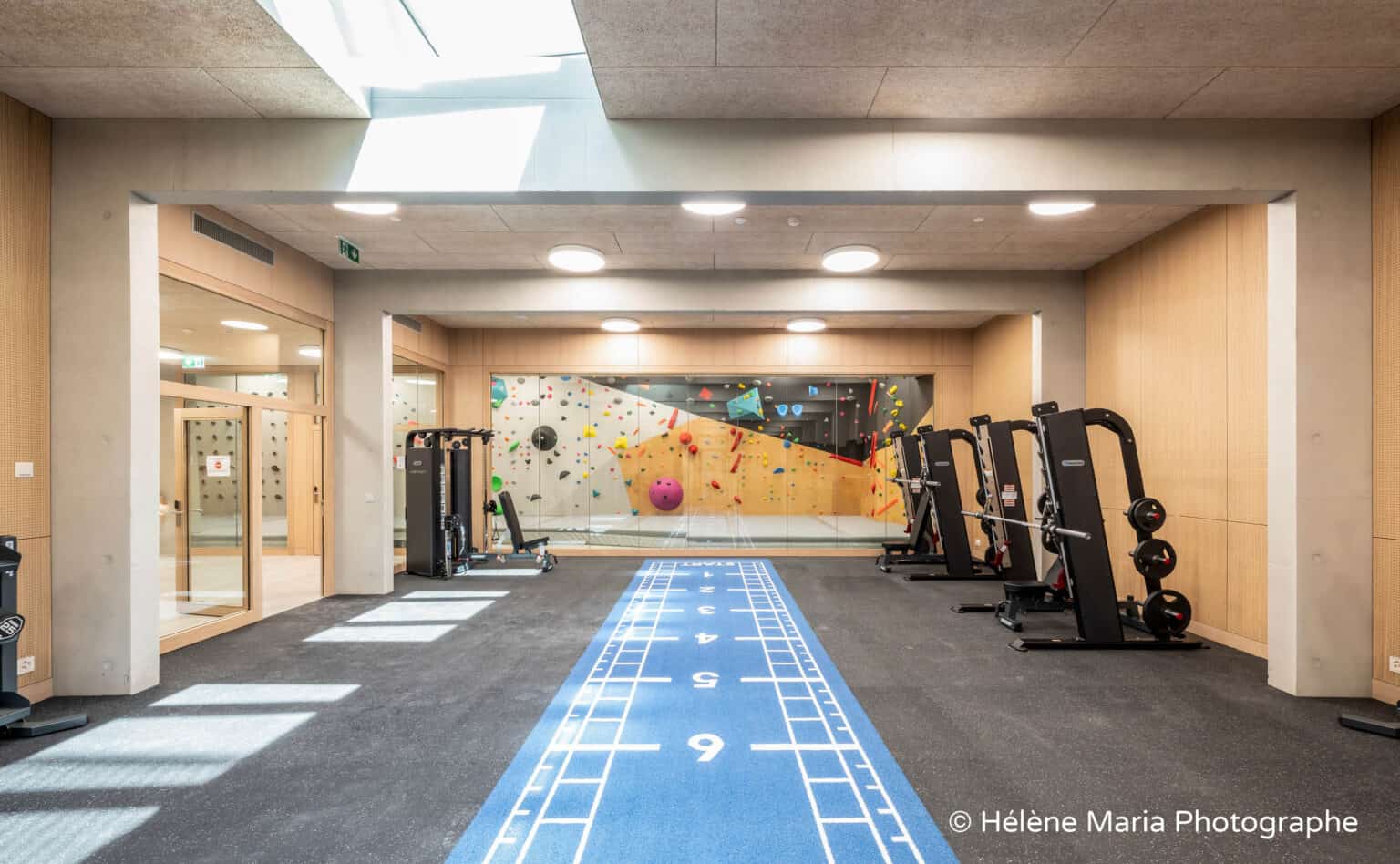 Modern school gym with climbing wall, fitness equipment, and indoor running track for student health and fitness.