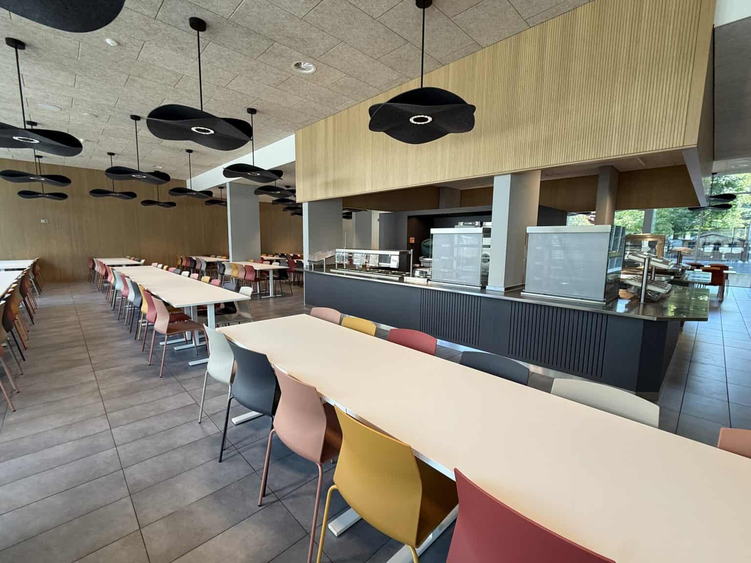 Bright modern school cafeteria with colorful chairs and stylish lighting, promoting a vibrant learning environment.