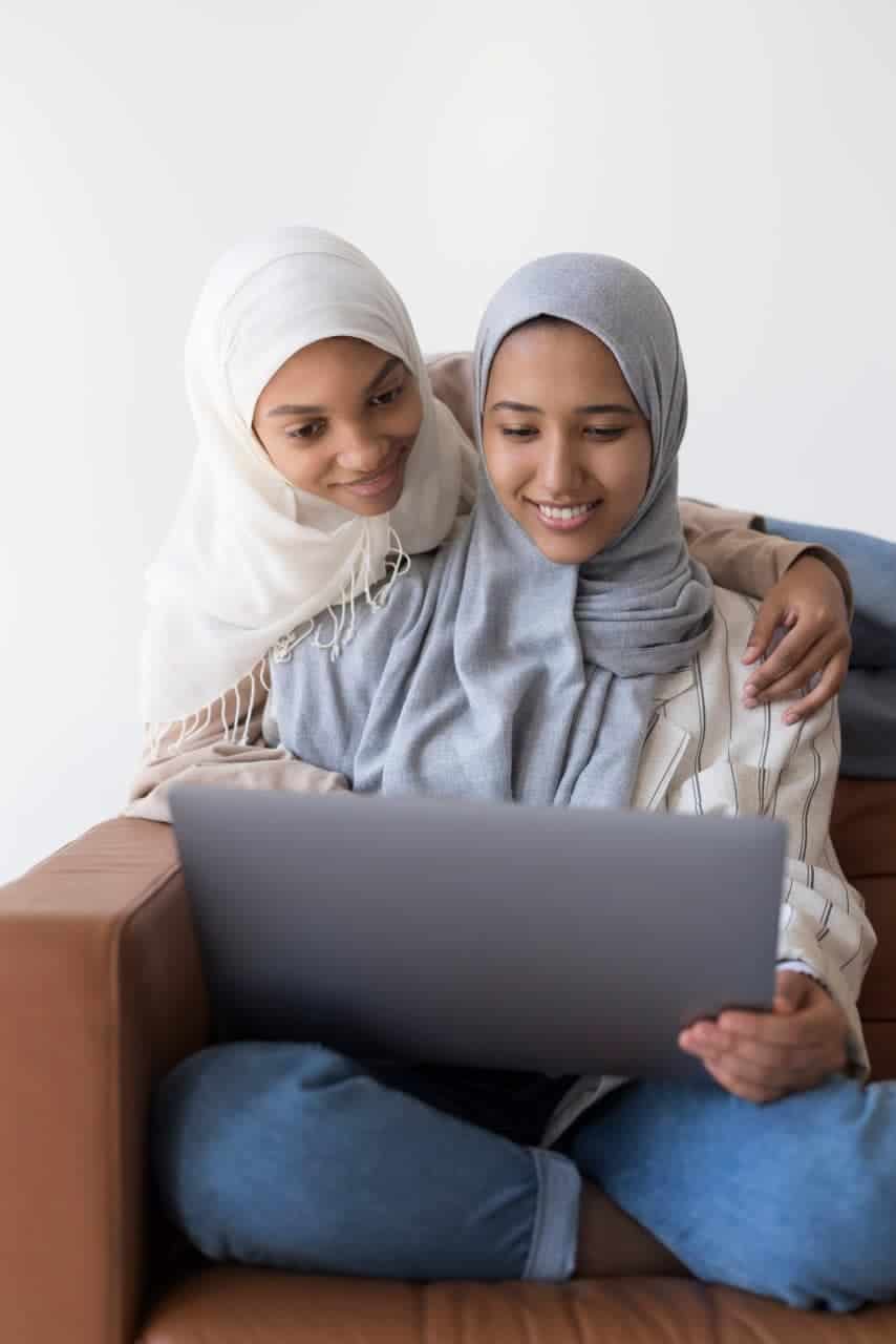 Child girls in hijabs studying with a tablet for online learning at home.