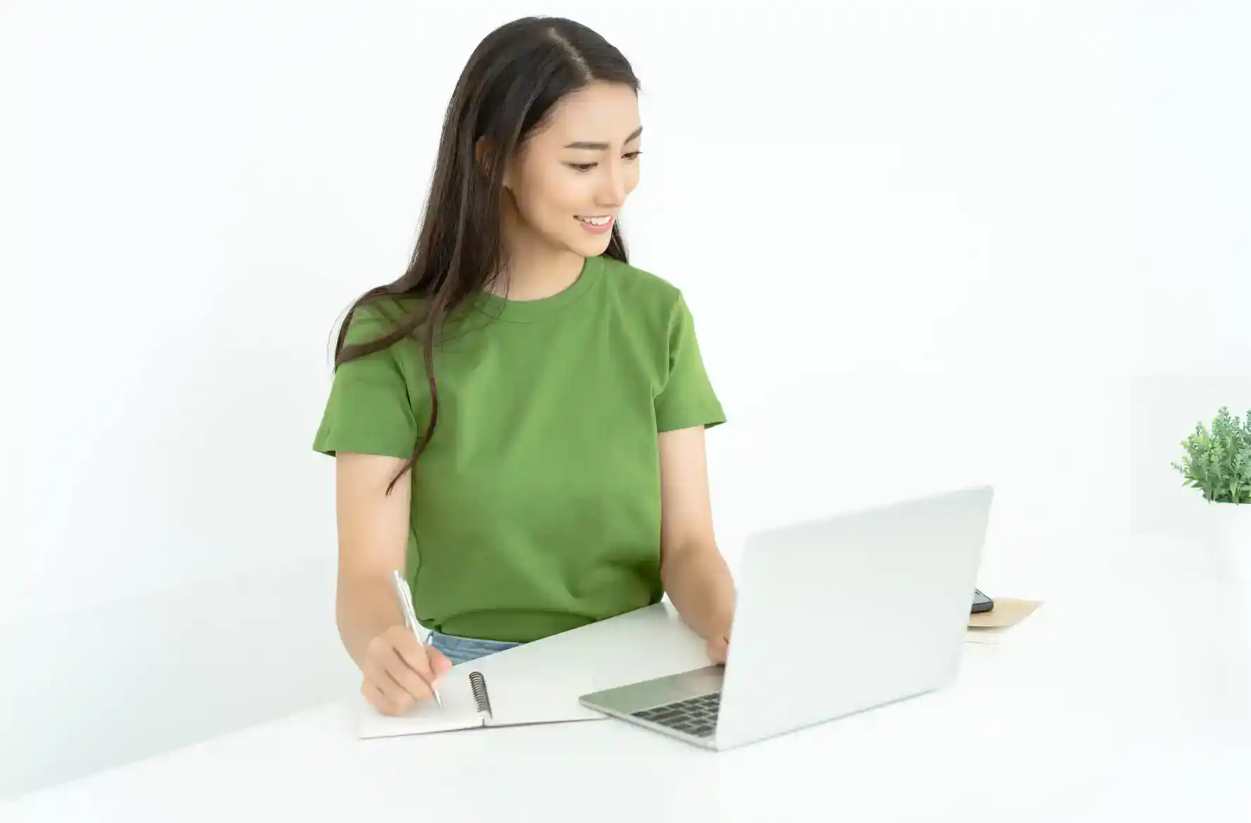 Young woman working on a laptop with notes at a clean, modern desk for world school education.