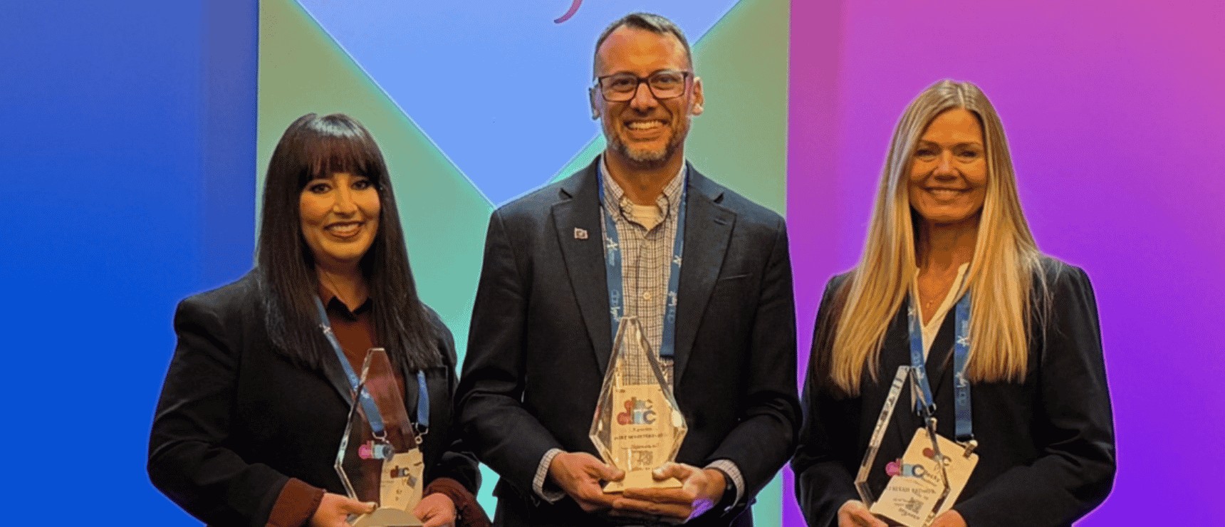 Three winners pose with glass trophies at a World Schools event.