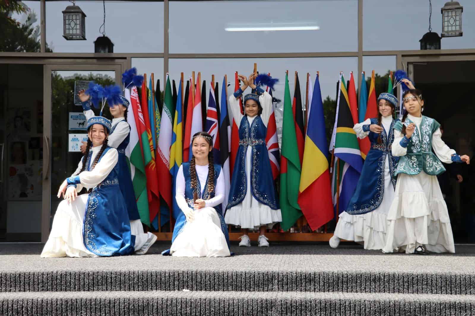 International students performing traditional dance in front of a display of world flags.