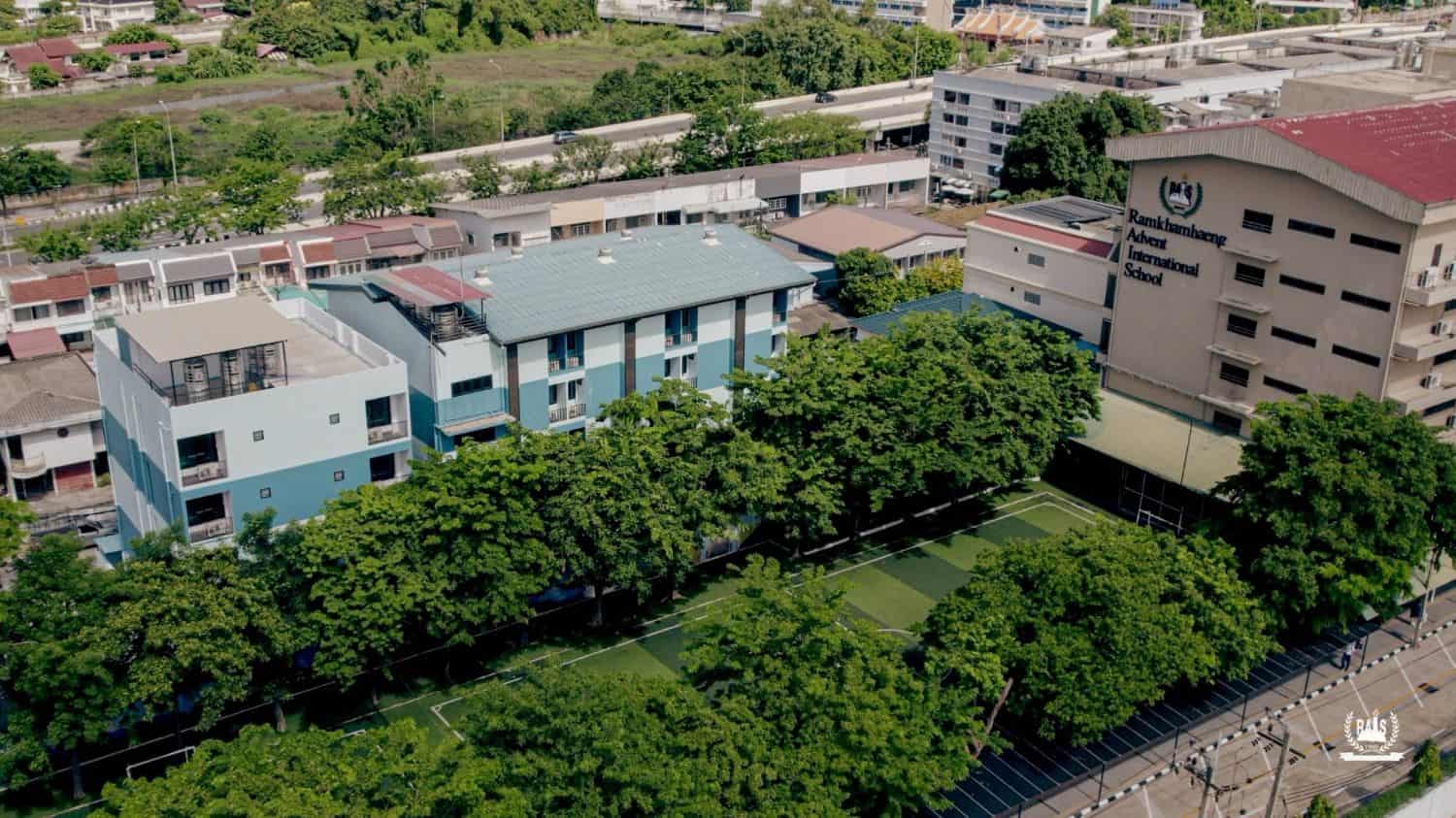 Aerial view of World Schools campus with modern buildings and green sports fields.