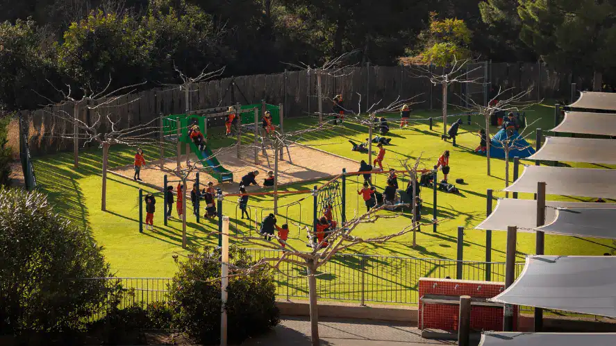 Vibrant outdoor playground at World Schools with children playing and engaging in sports activities.