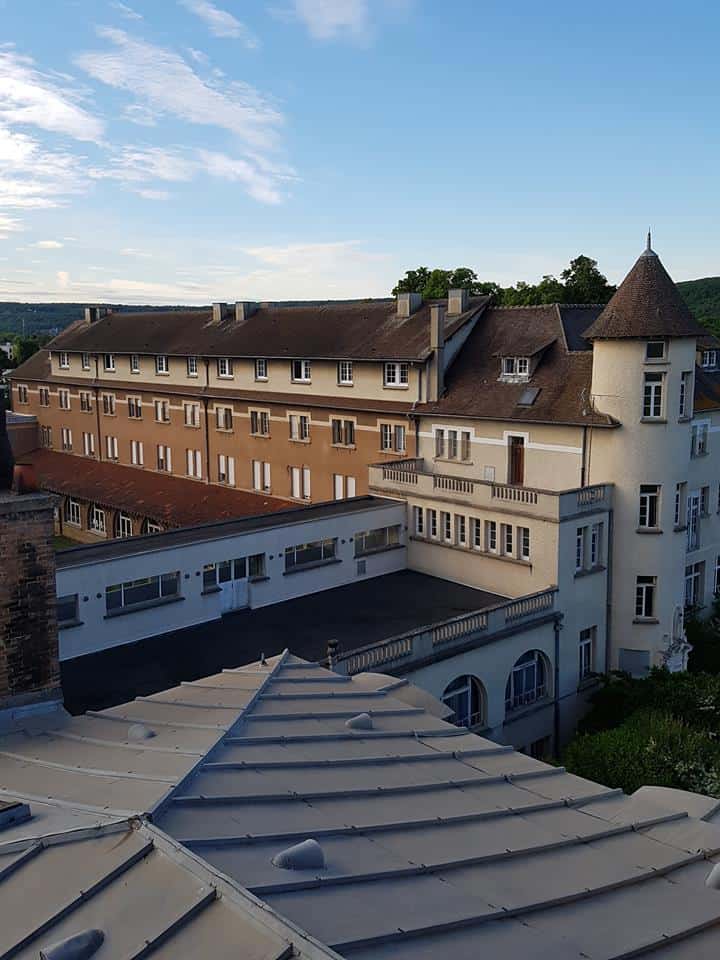 Elegant European-style school building with classic architecture and turret, situated in a scenic setting.