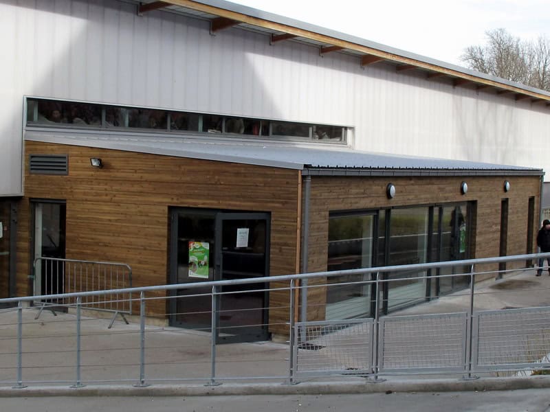 Modern school building with wooden facade and glass doors, part of the World Schools network.