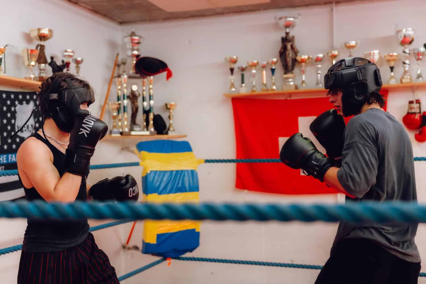 Female boxer training in a school boxing gym with trophies and sports equipment on the wall, emphasizing sports education at World Schools.