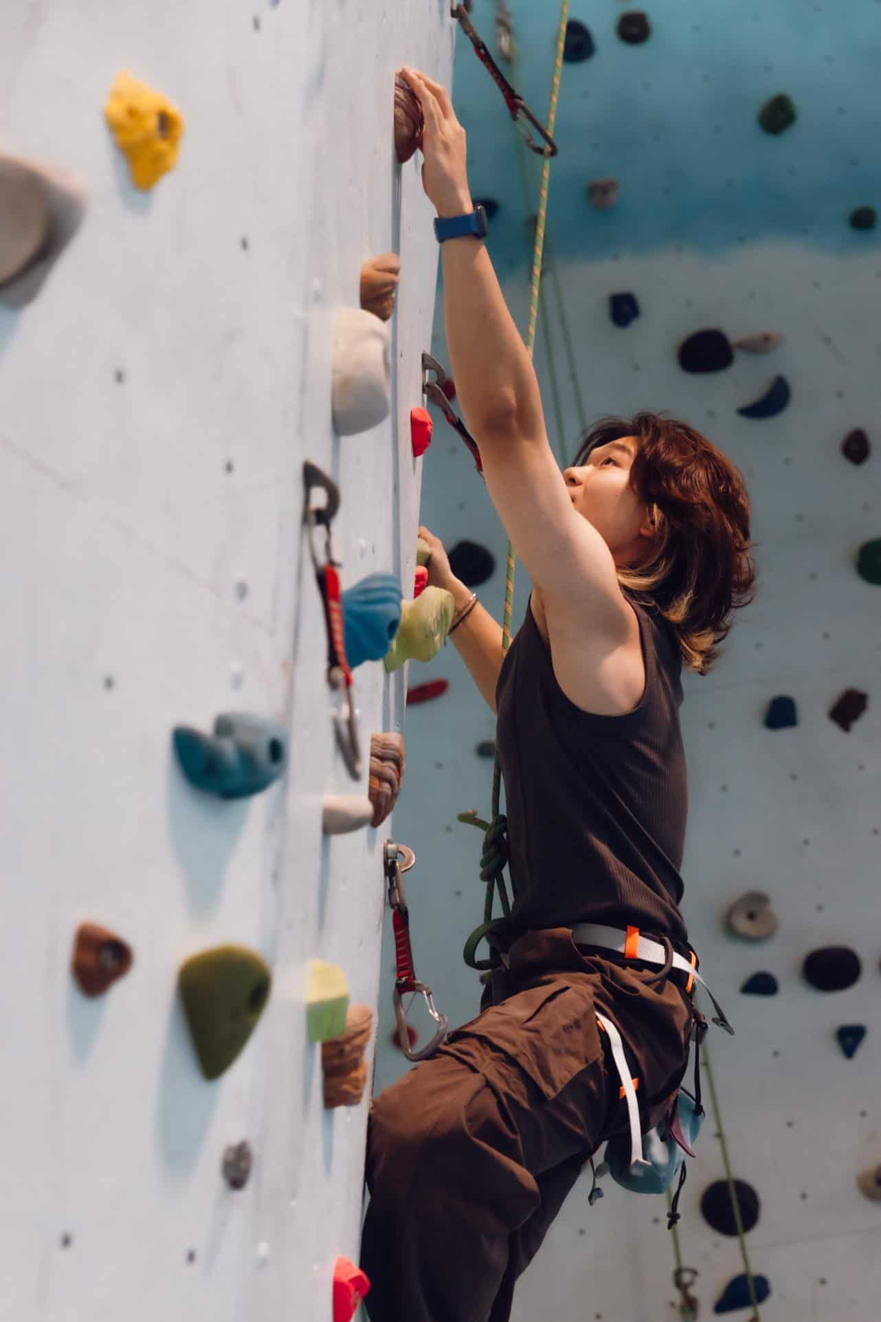 Young woman rock climbing at indoor gym for student achievement and physical development.