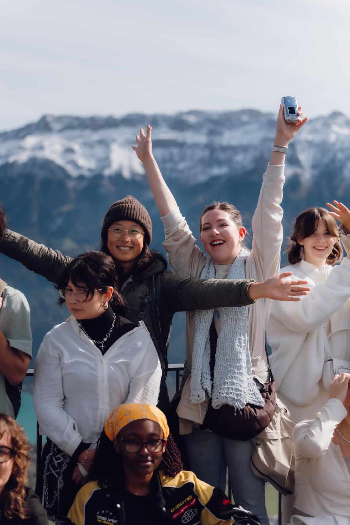 Diverse students smiling outdoors with snowy mountains, promoting international schools and global education excellence.