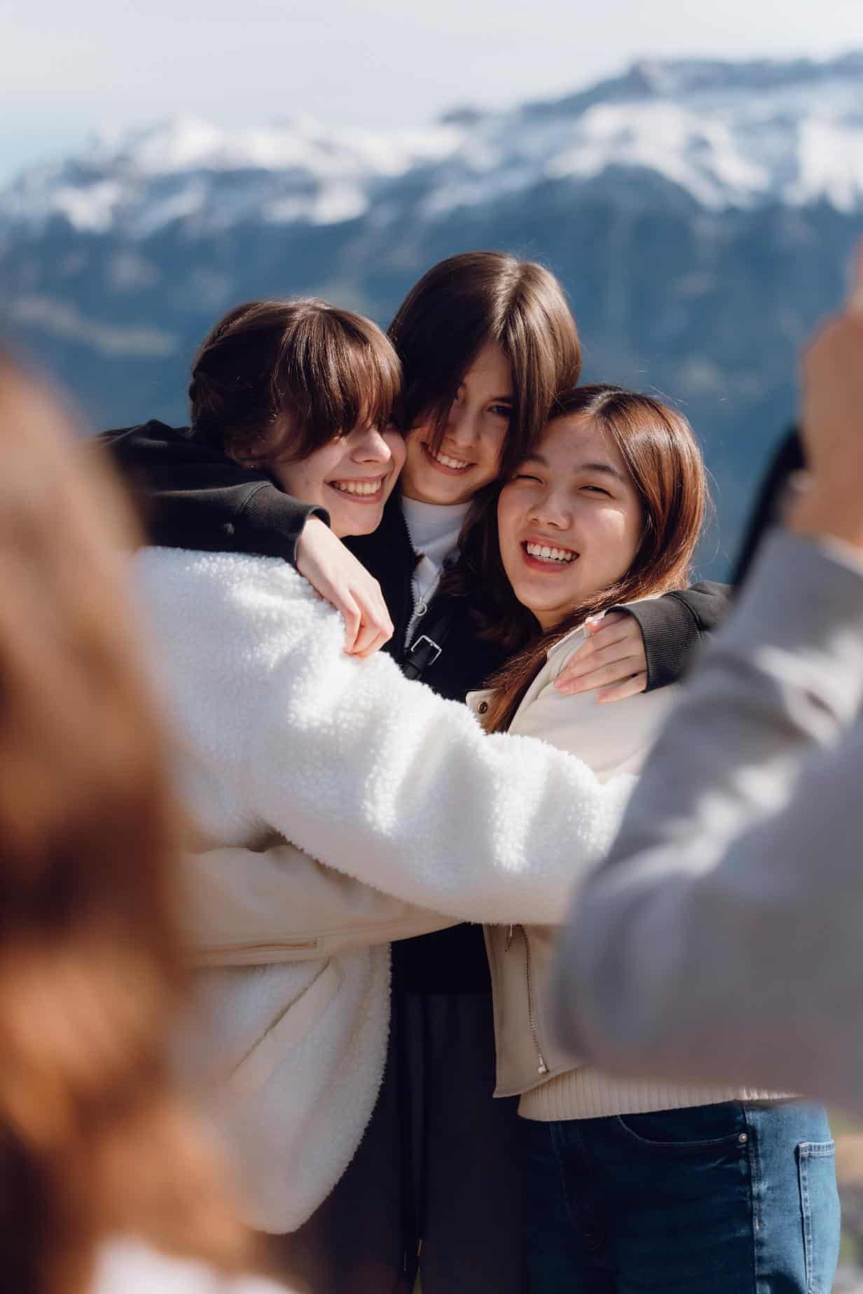 Smiling students embracing outdoors with snow-capped mountains, highlighting outdoor learning at World Schools.