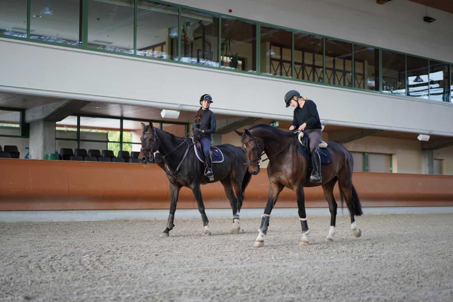 Elegant students horseback riding at a modern world school equestrian facility.