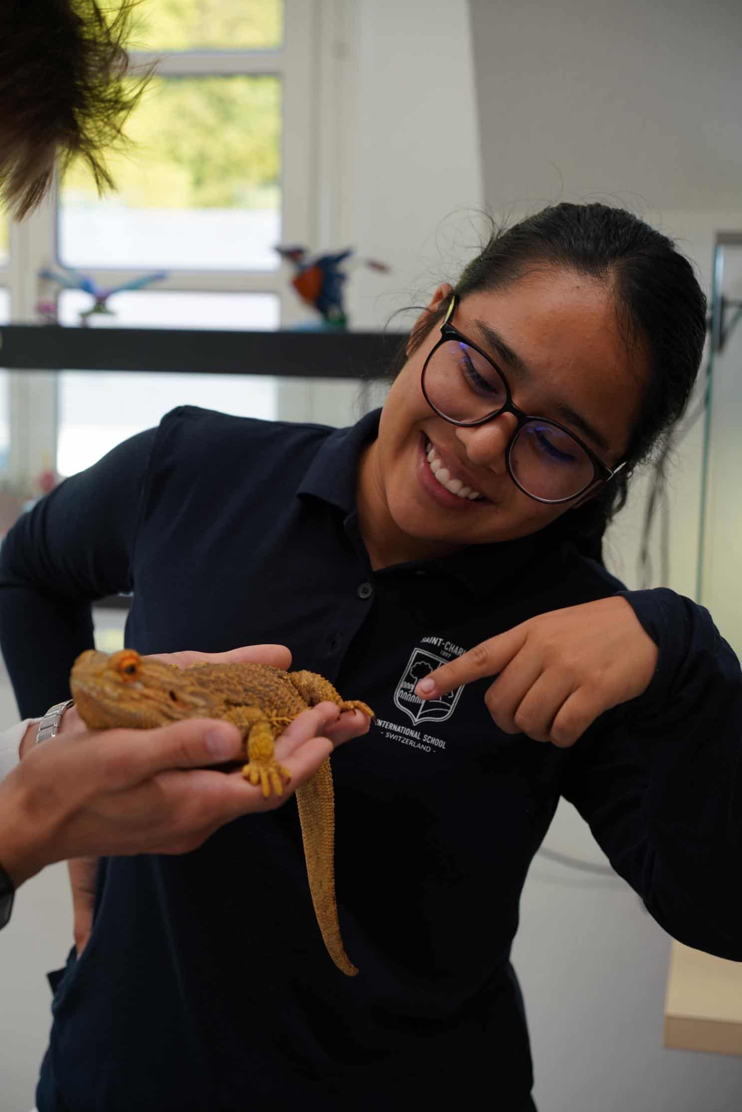 Bright student at World Schools taking part in animal science or biology class with a pet gecko.