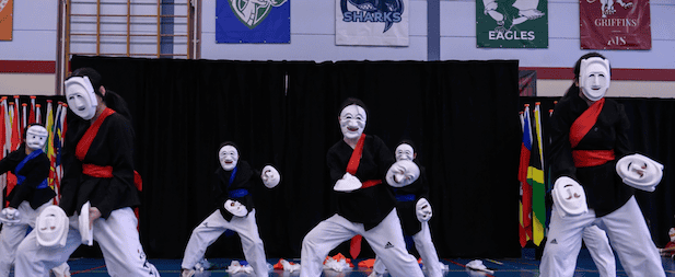 Performers in traditional martial arts costumes with white masks during a cultural display.
