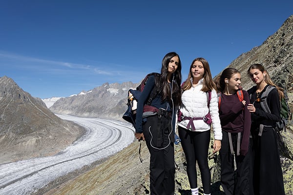Group of students hiking in mountain terrain with glacier in background.
