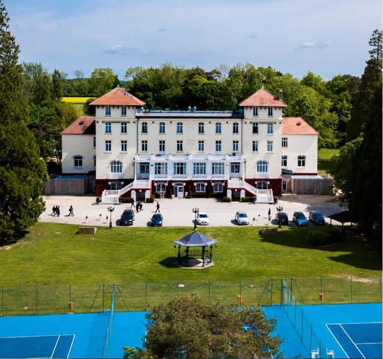 Main building of a world school with sports courts and green surroundings.